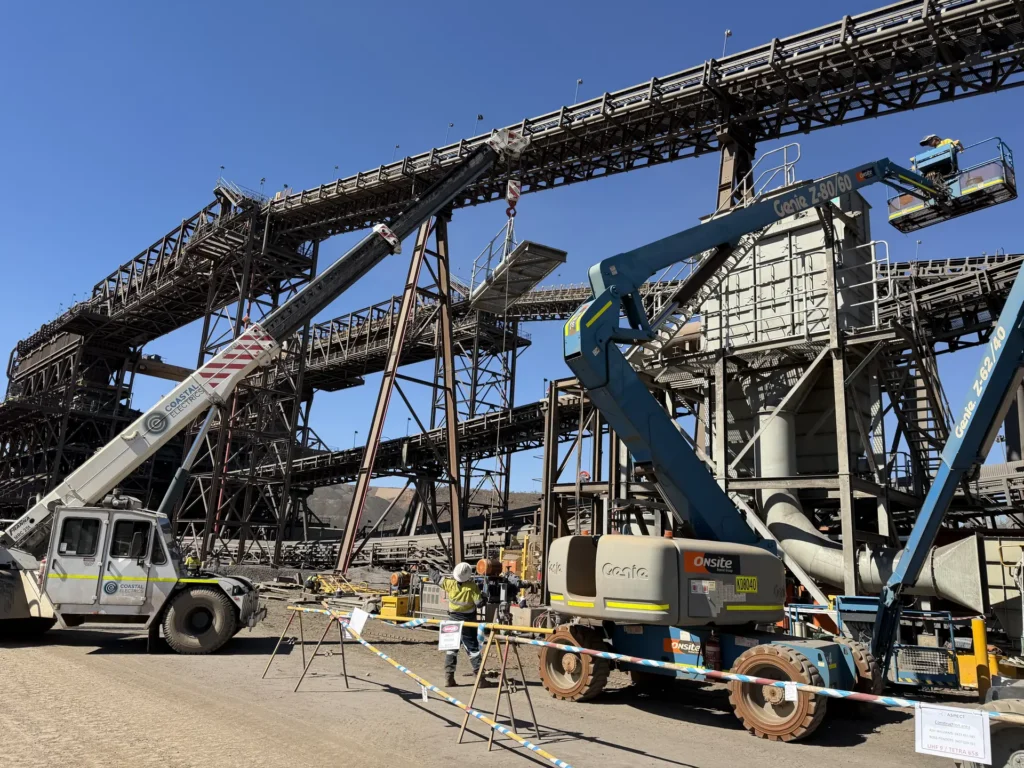 Mobile crane and elevated work platforms set up under conveyors during a plant shutdown