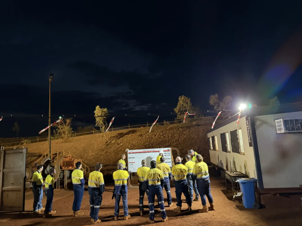 Crew in hi-vis gathered for a night shift prestart meeting on site